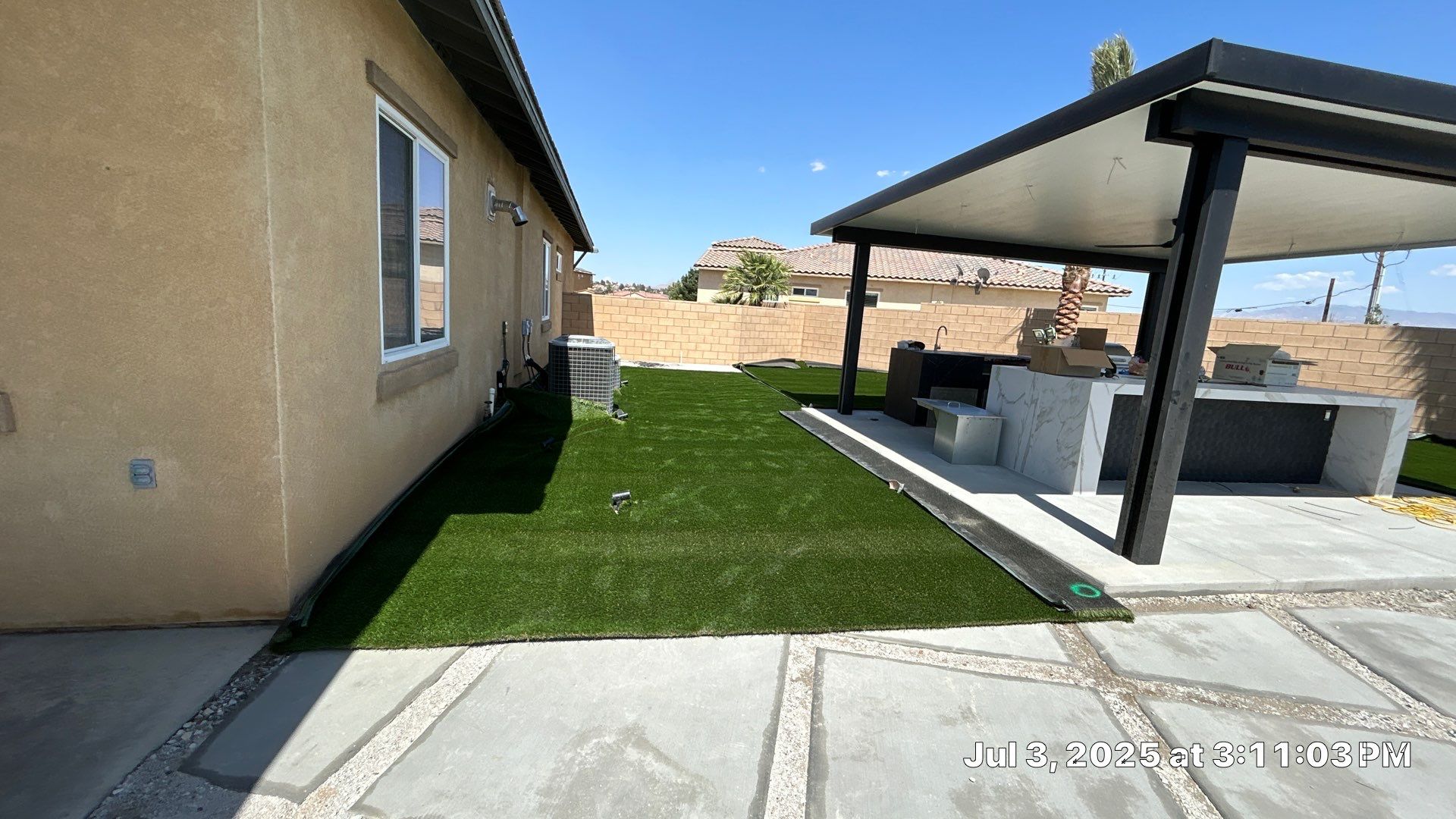 Backyard turf install with patio cover, outdoor kitchen, and pool