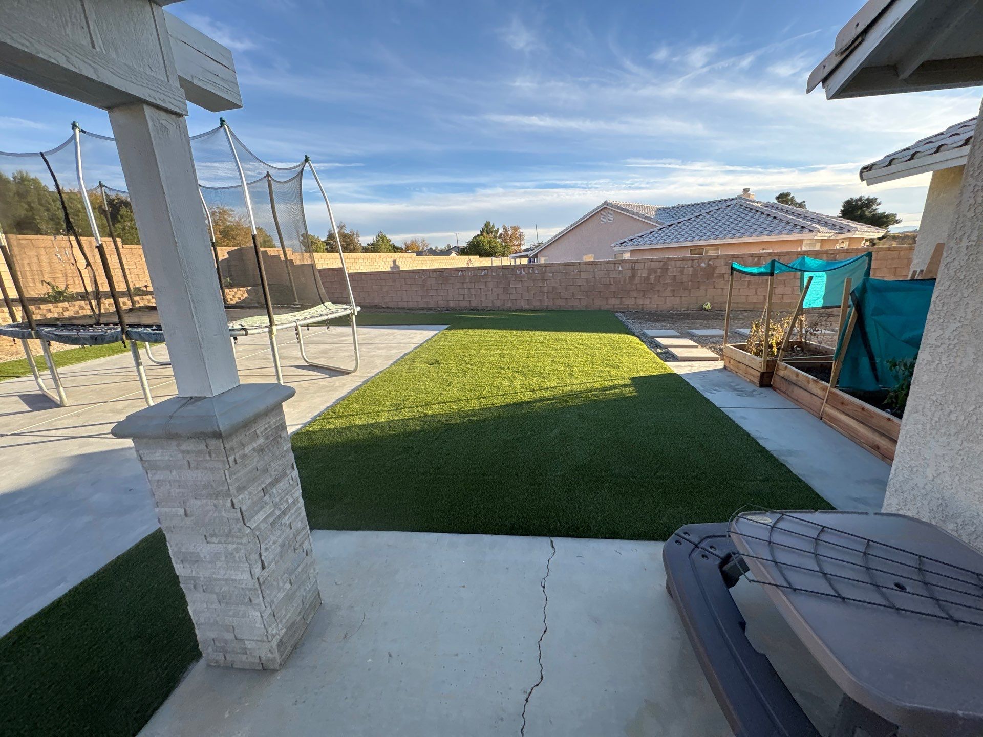 Backyard turf with pergola, trampoline, and garden beds